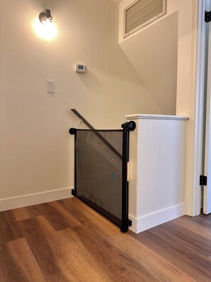 A room with a wooden floor, a white wall, a ceiling light, a thermostat, and a black screen door. - 4min walk to Downtown Flagstaff 2bd/1.5ba NEW! (Flagstaff)