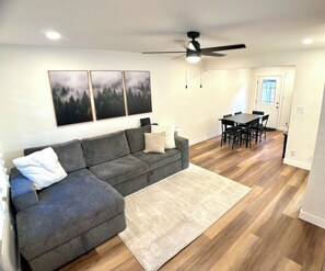 A living room with a gray sectional sofa, a white rug, a dining table with chairs, and a ceiling fan. - 4min walk to Downtown Flagstaff 2bd/1.5ba NEW! (Flagstaff)