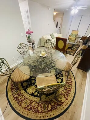 A dining area with a glass-top table surrounded by chairs, a patterned rug, and a flower vase. - Atlanta Gem Near Stone Mountain Park Lithonia Snellville Stonecrest (Stone Mountain)