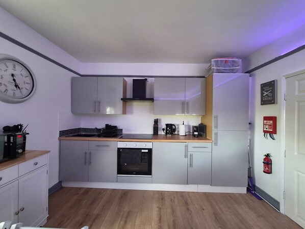 A compact kitchen with grey cabinets, a microwave, a stove, and a coffee maker. - Wellsway View (Bath)