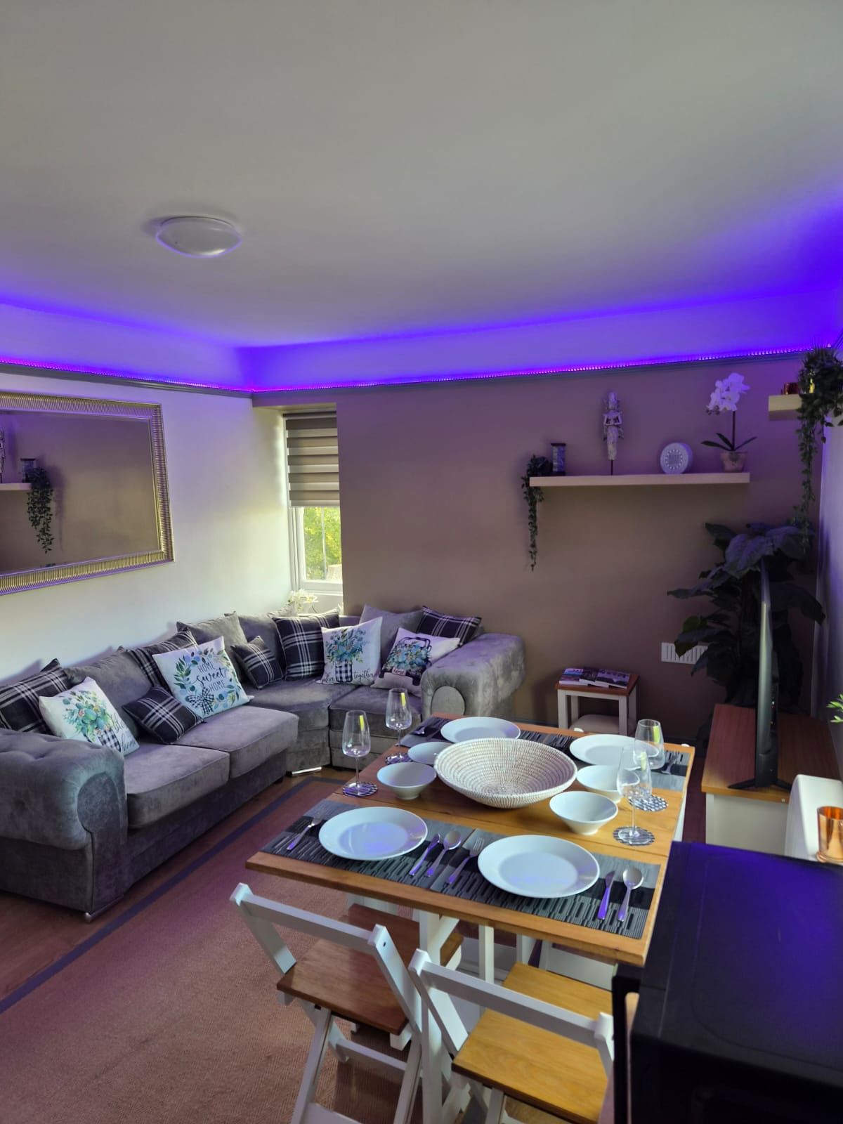 A dining area with a table set for four, a sofa, and a window with blinds.