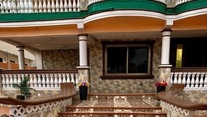 A grand staircase leading to a balcony with a stone wall and a large window.