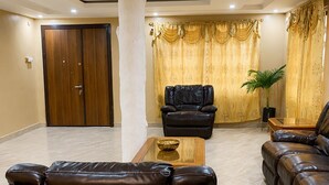 A spacious living room with a leather sofa, a coffee table, and a black armchair.