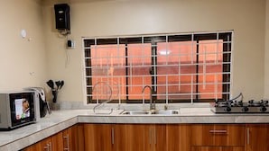 A kitchen with wooden cabinets, a stainless steel sink, and a window with orange curtains.