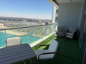 Ein Balkon mit Blick auf eine Küstenstadt, einen Pool und Rasenfläche.