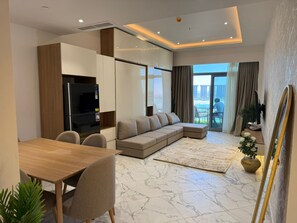 Ein modernes Wohnzimmer mit Ecksofa, Esstisch und Küchenzeile, inklusive Kühlschrank und Schränken.