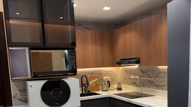 A modern kitchen with a built-in microwave, a coffee maker, and a sink. - Luxury 1-bedroom in Gate tower with double View (New Alamein)