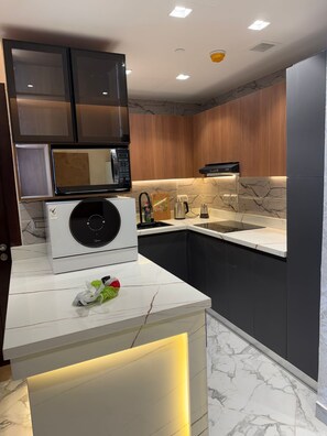 A modern kitchen with a built-in microwave, a coffee maker, and a sink. - Luxury 1-bedroom in Gate tower with double View (New Alamein)