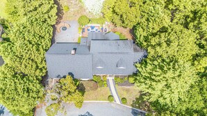 Ett flygbildsfoto av en bostadsfastighet med ett stort hus, en inhägnad trädgård och omgivande träd.