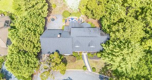 An aerial view of a residential property with a large house, a fenced yard, and surrounding trees. - The Mad Hatter Inn - In the Village of Pinehurst! (Pinehurst)