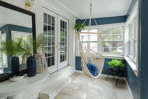 A room with a white door, a hanging chair, and a potted plant. - The Mad Hatter Inn - In the Village of Pinehurst! (Pinehurst)