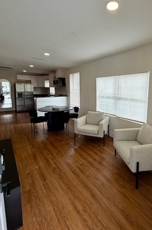 A spacious living area with a wooden floor, a dining table with chairs, and a sofa. - Golden safari home Perfect Getaway for Relaxation (Tampa)