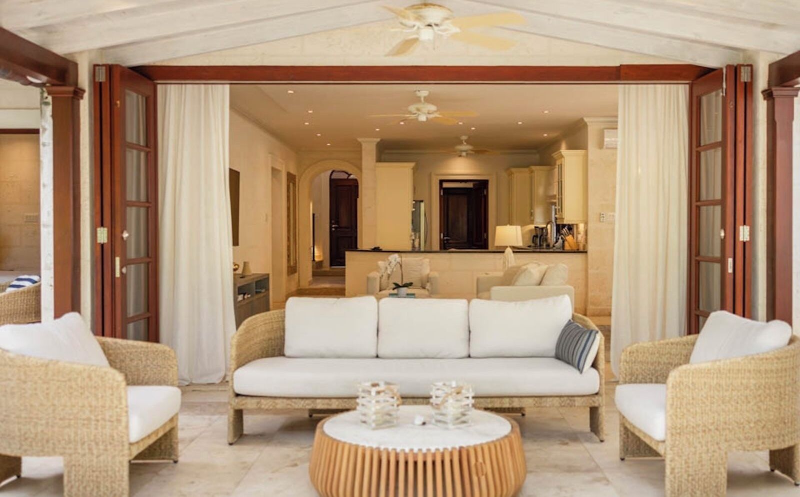 A hotel room with a sofa set, a round coffee table, and a view into the adjacent room.