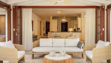 A hotel room with a sofa set, a round coffee table, and a view into the adjacent room.