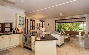 A spacious kitchen with a central island, a dining area with a sofa, and a view of tropical vegetation. - Claridges 5 - 3bd by Zenbreak (Gibbes)