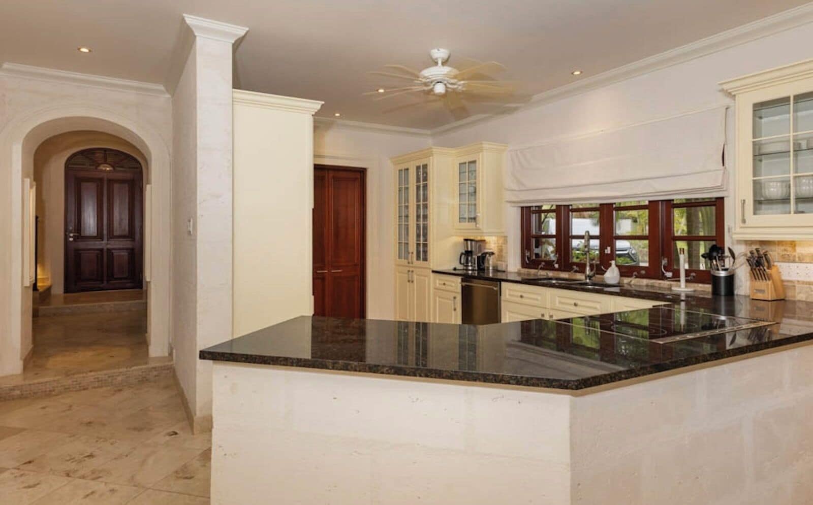 A spacious kitchen with a large island, white cabinetry, and a ceiling fan.