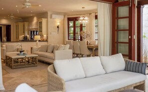 Amplia sala de estar con sofá, sillas, una mesa de centro y un comedor con candelabro.