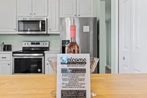 Un letrero de bienvenida en una cocina con una botella de vino, un bol y un tostador.