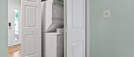 A laundry room with a washer and dryer, a basket, and a door leading to another room.