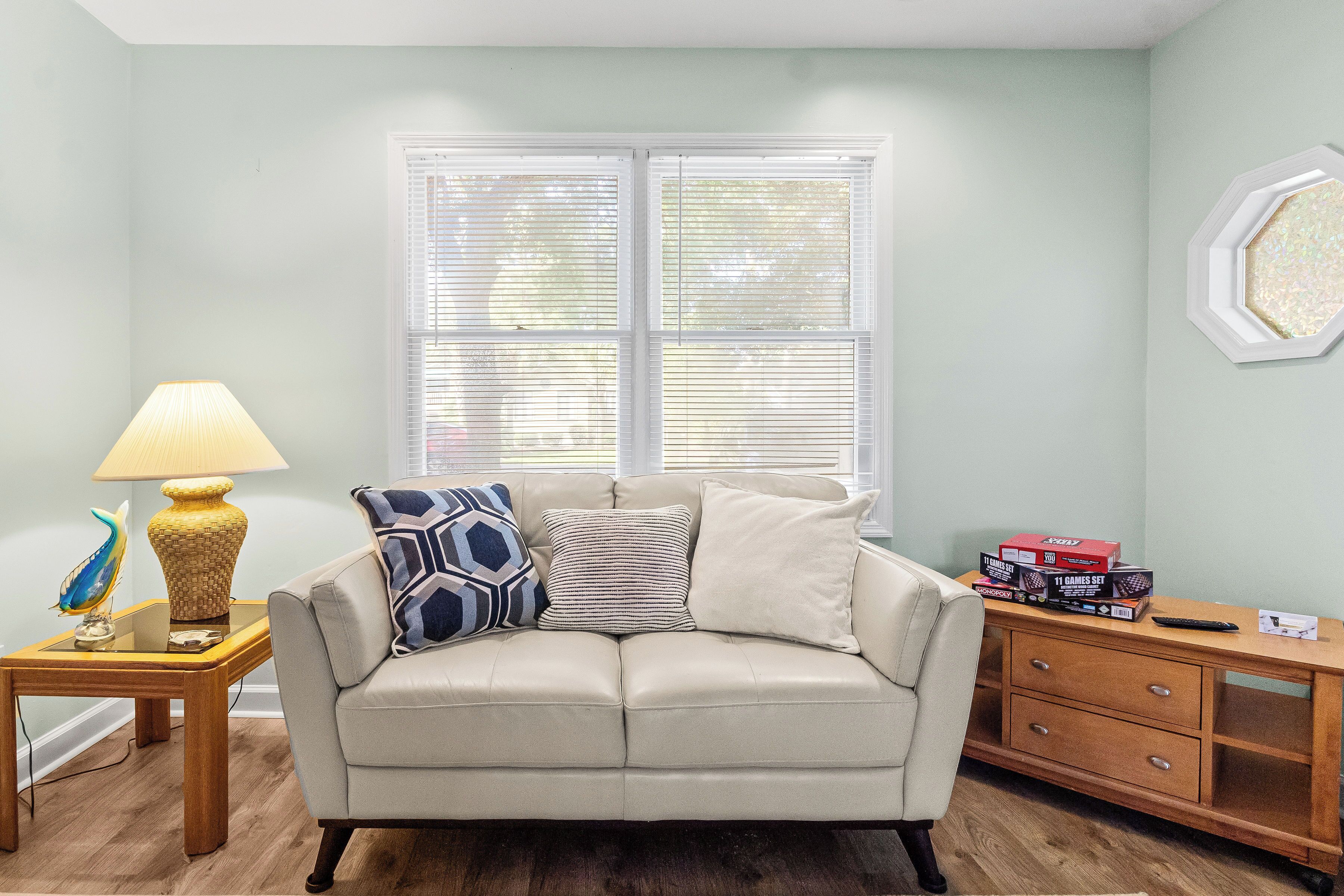 A living room with a beige sofa, patterned pillows, a lamp, and a side table.