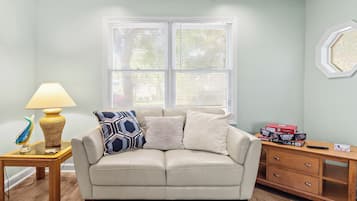 A living room with a beige sofa, patterned pillows, a lamp, and a side table.