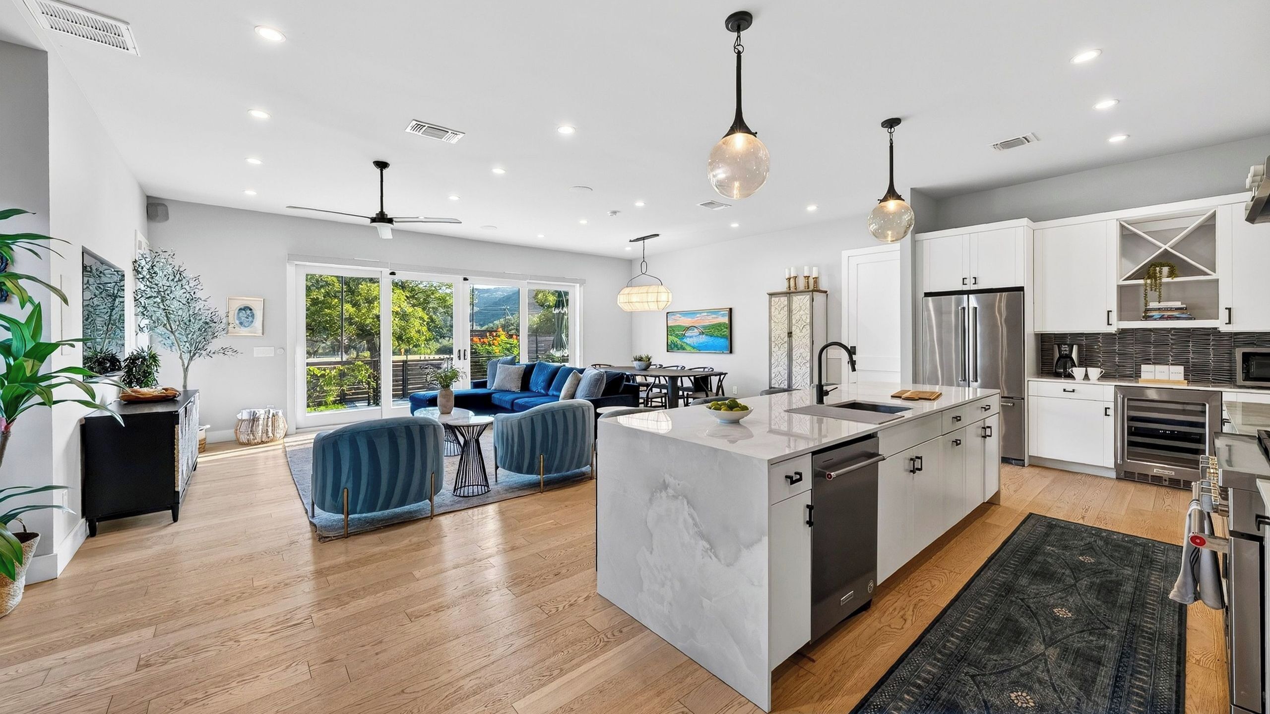 A modern kitchen with a central island, built-in appliances, and a dining area with blue sofas.