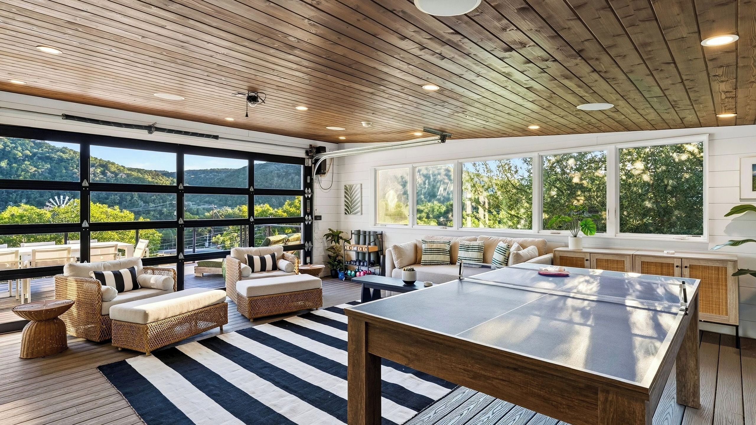 Una habitación espaciosa con un gran techo de madera, una mesa de ping pong y vistas a un paisaje montañoso a través de amplios ventanales.