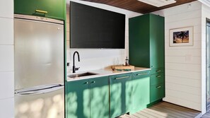 Une cuisine avec des meubles de couleur verte, un plan de travail blanc et un pare-feu noir.