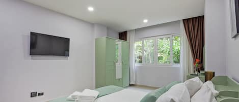Une chambre à coucher avec un lit, une armoire, une télévision et une fenêtre avec des rideaux.