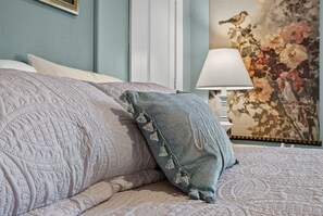 A bed with a textured quilt and a decorative pillow.