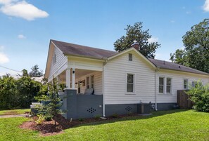 A single-story house with a front porch, a chimney, and a small front yard.