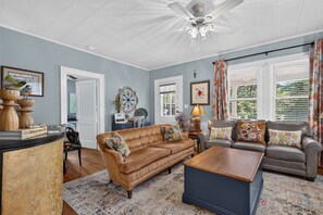 A living room with a brown sofa, a blue coffee table, and a patterned rug. - Side Street Bungalow -Close to Town/Shopping/Tryon Equestrian Center/Restaurants (Forest City)