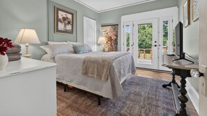 Ein Schlafzimmer mit einem Bett, zwei Nachttischlampen, einem Deckenventilator und einer Tür, die auf einen Balkon führt.
