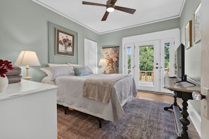 A bedroom with a bed, two bedside lamps, a ceiling fan, and a door leading to a balcony. - Side Street Bungalow -Close to Town/Shopping/Tryon Equestrian Center/Restaurants (Forest City)