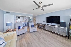 A living room with a sofa, armchairs, a television, and a ceiling fan. - Emerald Beach - A Gulf Front Resort Experience (Panama City Beach)