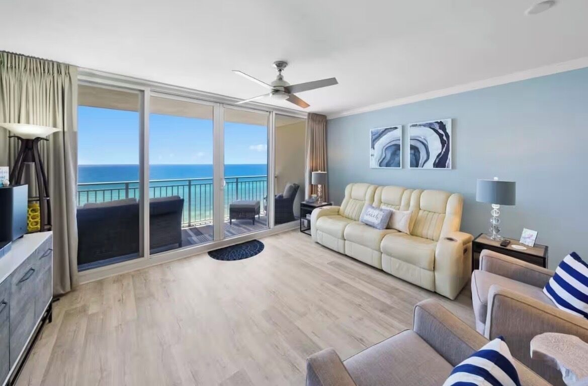 A spacious living area with a balcony, a sofa, a coffee table, and a ceiling fan.