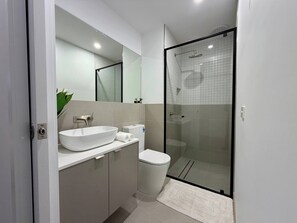 Ein modernes Badezimmer mit Waschbecken, Toilette und einer Duschkabine.