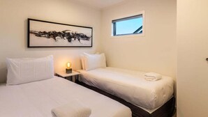 A hotel room with two beds, a nightstand, a wall-mounted painting, and a window. - Views on Beachman - pet friendly with lake views (Taupo)