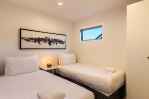 A hotel room with two beds, a nightstand, a wall-mounted painting, and a window. - Views on Beachman - pet friendly with lake views (Taupo)