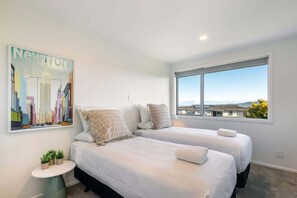 A hotel room with two beds, a large window, and a cityscape painting on the wall. - Views on Beachman - pet friendly with lake views (Taupo)