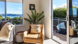 A balcony with a view of the sea, a chair with a cushion, and a small table. - Views on Beachman - pet friendly with lake views (Taupo)