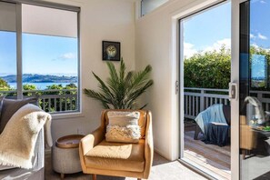 A balcony with a view of the sea, a chair with a cushion, and a small table. - Views on Beachman - pet friendly with lake views (Taupo)