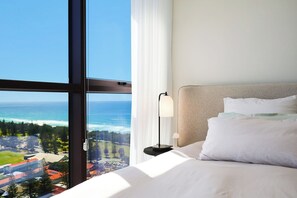 A hotel room with a large window offering a view of the ocean and a distant landscape. - Luxe Escape at Yves at Mermaid Beach (Mermaid Beach)