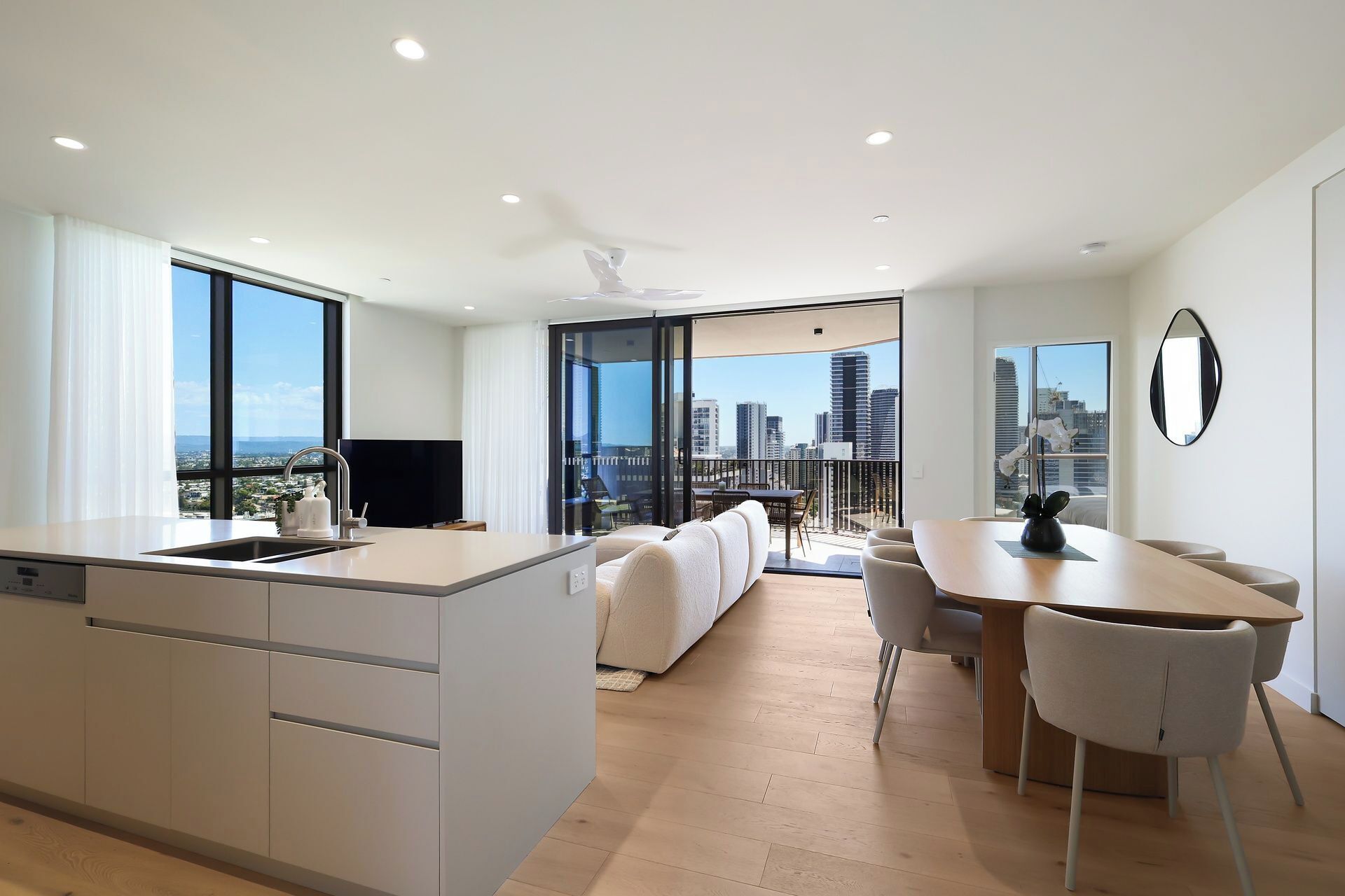 Un appartement moderne doté d’une cuisine, d’un coin repas et d’un balcon offrant une vue sur la ville.