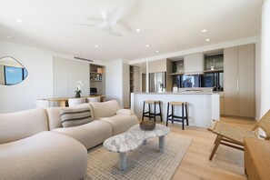 Una sala moderna con un sofá, una mesa de centro y un comedor con taburetes.