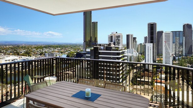 A balcony with a view of a cityscape, including high-rise buildings and a distant mountain range. - Luxe Escape at Yves at Mermaid Beach (Mermaid Beach)