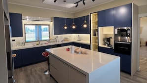 A modern kitchen with a central island, built-in appliances, and pendant lighting.