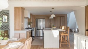 Eine moderne Küche mit Holzschränken, Edelstahlgeräten und einer zentralen Kochinsel mit Sitzgelegenheit.