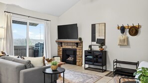 A modern living room with a fireplace, a sofa, a television, and a dining area. - Powder Perch by Avantstay Hot Tub + Pool + Mountain-view Balcony Mins to the Slopes + Trails (Park City)