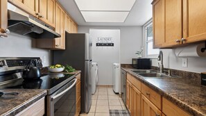 A compact kitchen with wooden cabinets, a stainless steel refrigerator, a built-in oven, and a microwave. - Powder Perch by Avantstay Hot Tub + Pool + Mountain-view Balcony Mins to the Slopes + Trails (Park City)